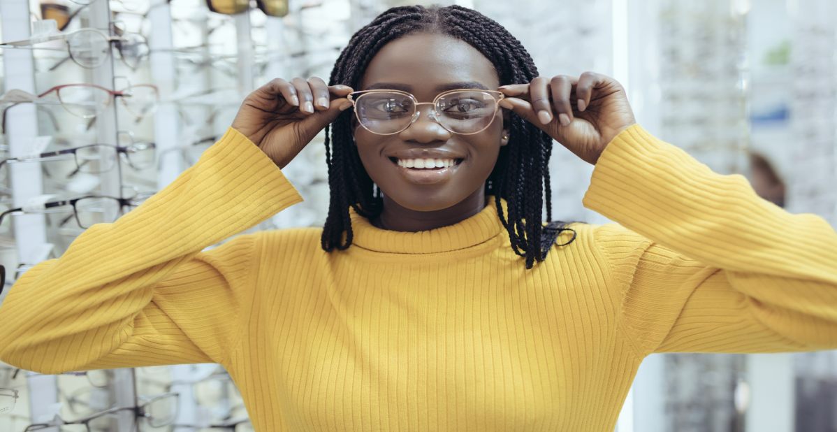 Young pretty african woman choosing prescription glasses frames in Optician's shop.