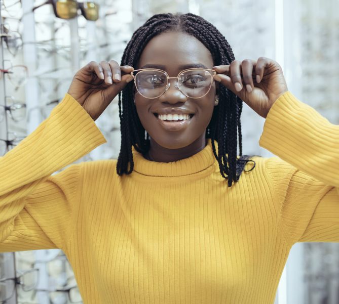 Young black woman optician in glasses choosing frames for clients in optician shop